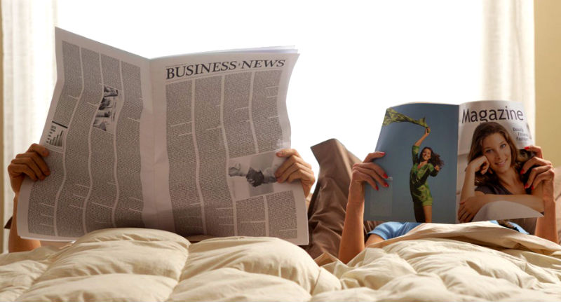 ベッドで新聞と雑誌を読むカップル