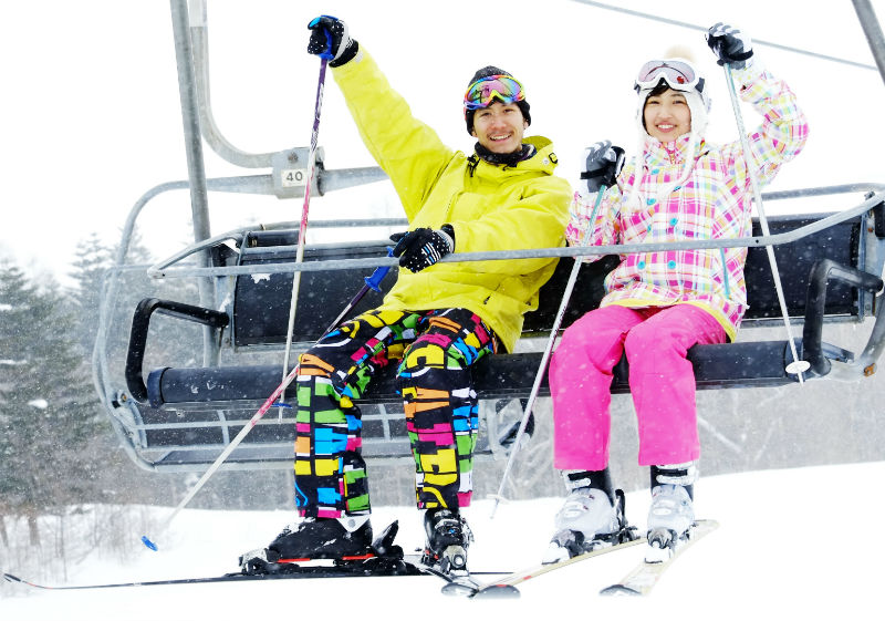 スキー場でリフトに乗るカップル