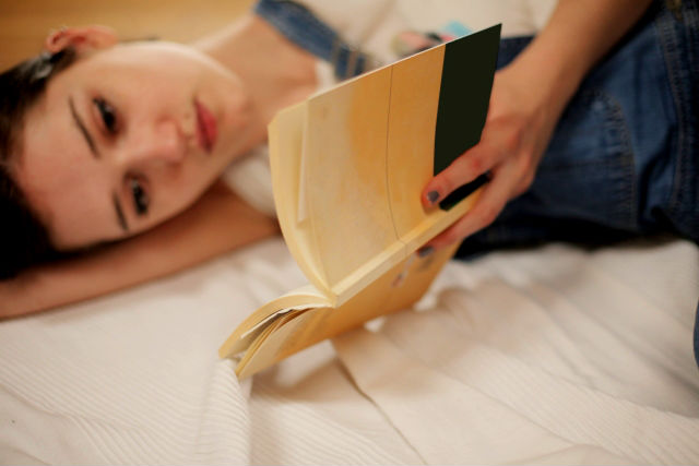 寝転んで本を読む女性
